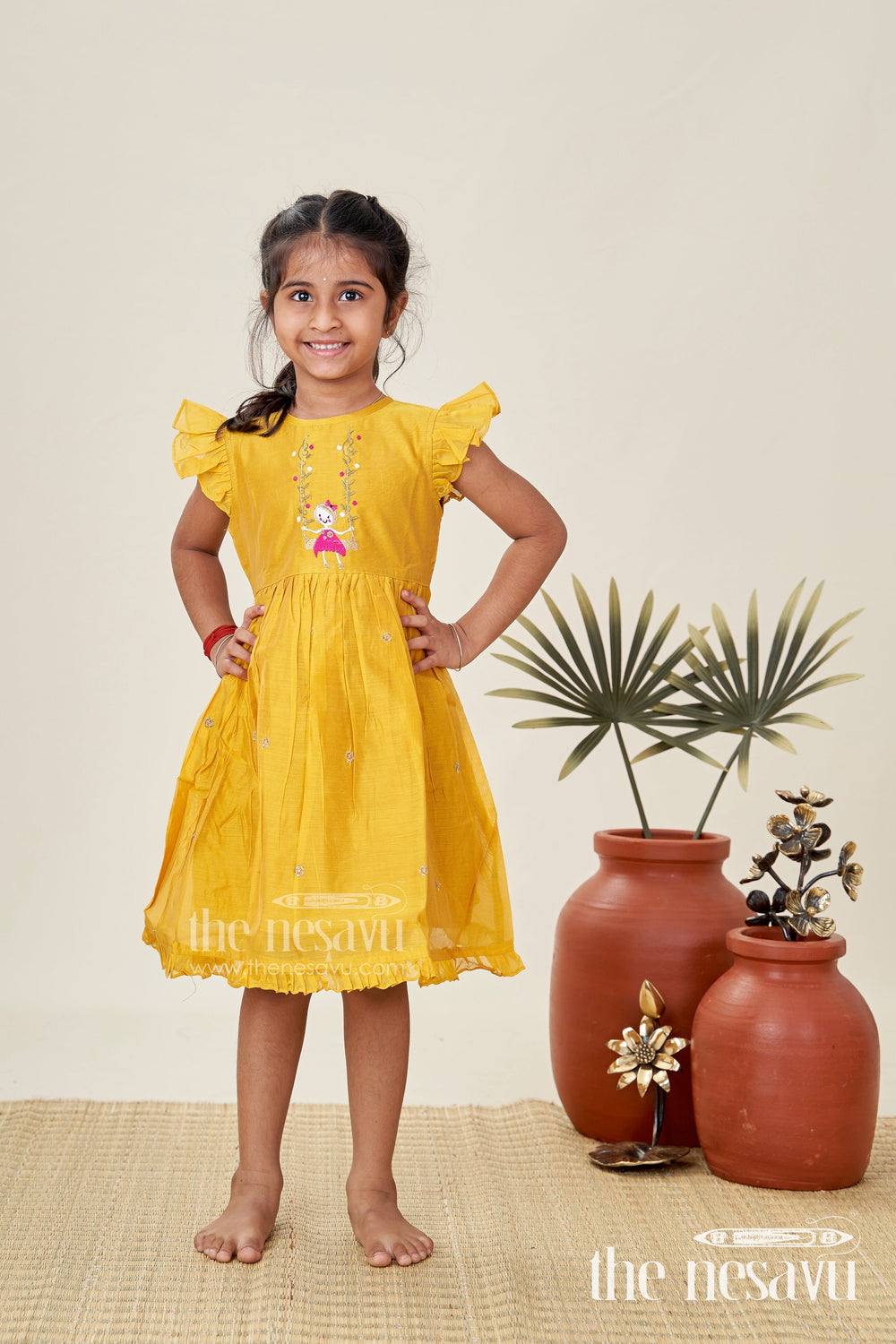 The Nesavu Girls Chanderi Frock Girls Chanderi Cotton Simple Frock Design with Swing Embroidery and Frill Sleeves in Honey Yellow Nesavu Nesavu Girls Chanderi Cotton Honey Yellow Frock Swing Motif Simple Frill Sleeve Design