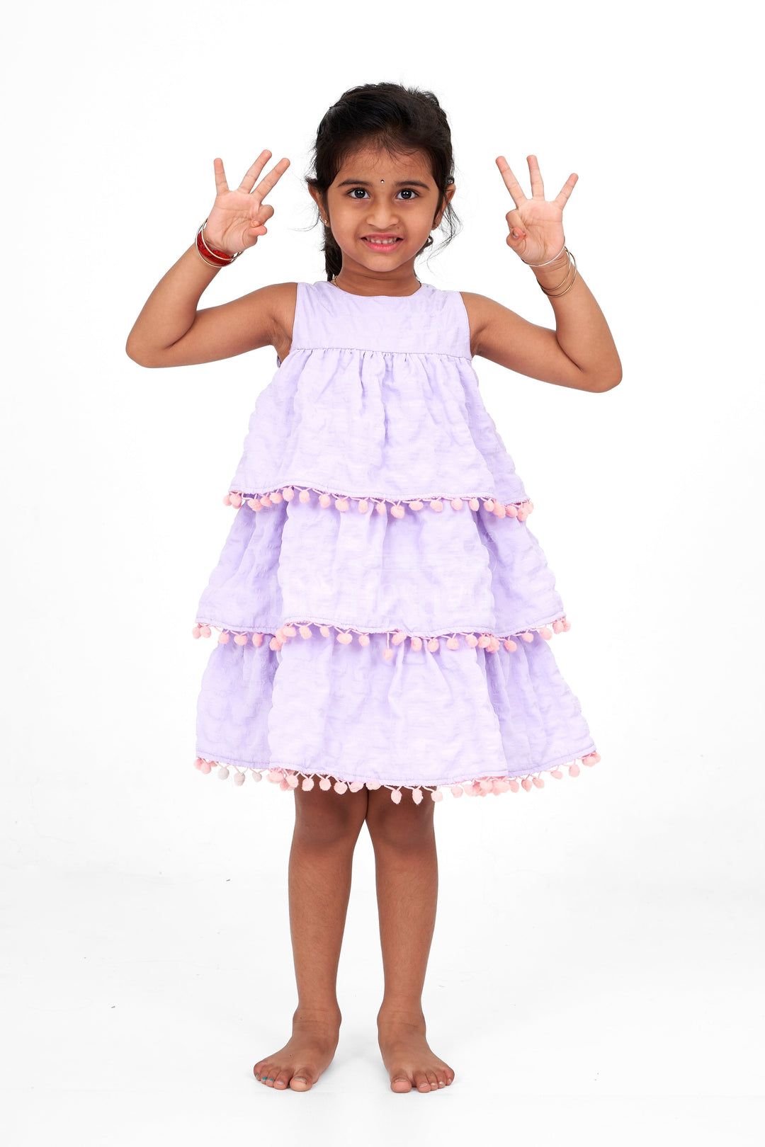 The Nesavu Girls Fancy Frock Lilac-Tiered Girls Fancy Frock with Pom-Pom Trim and Sleeveless Design for Parties Nesavu Nesavu Lilac-Tiered Girls Fancy Frock Pom-Pom Trim Textured Fabric Birthday Parties