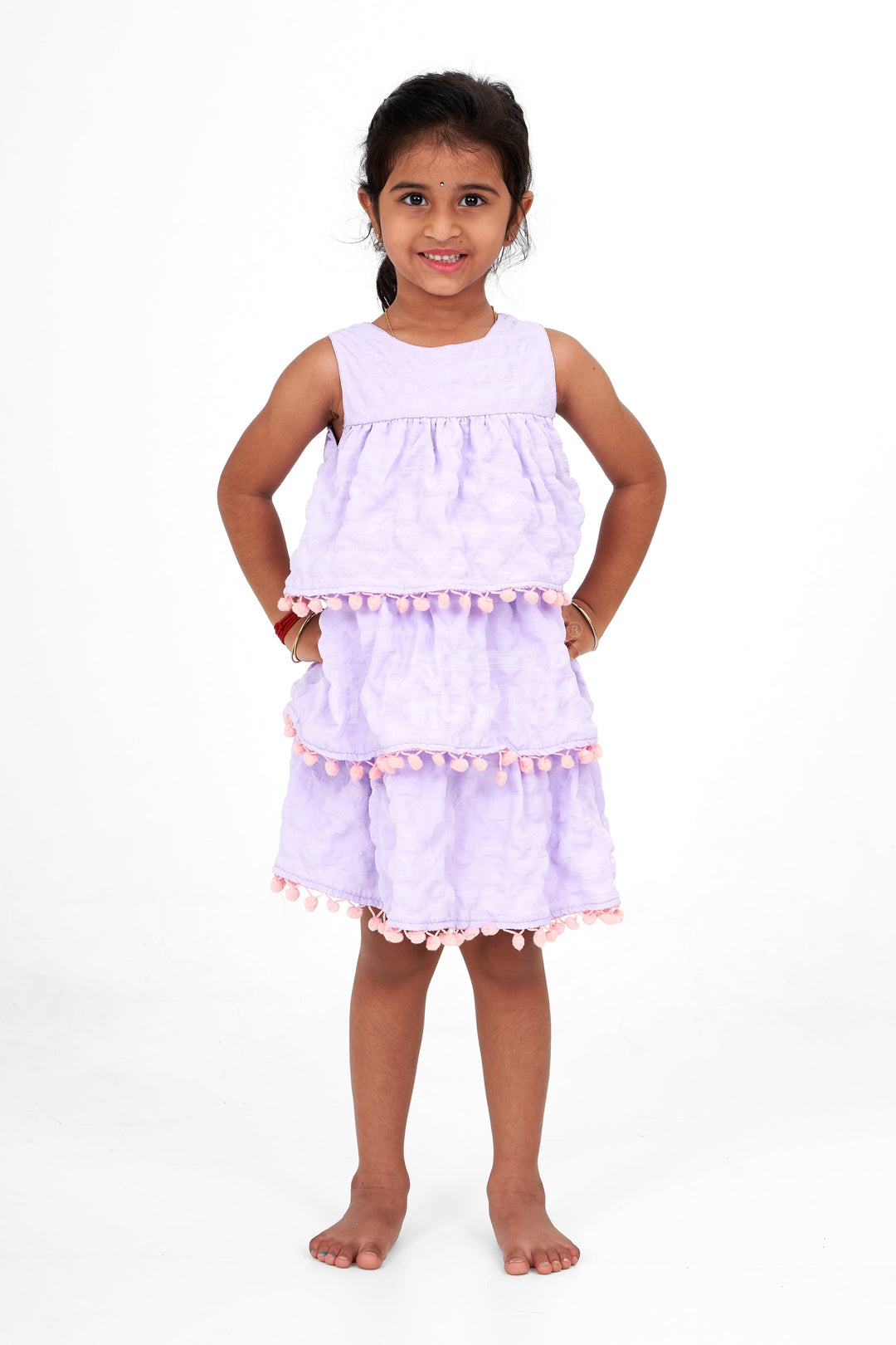 The Nesavu Girls Fancy Frock Lilac-Tiered Girls Fancy Frock with Pom-Pom Trim and Sleeveless Design for Parties Nesavu Nesavu Lilac-Tiered Girls Fancy Frock Pom-Pom Trim Textured Fabric Birthday Parties